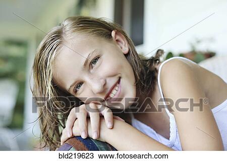 Stock Image - Close up of smiling girl leaning in armchair. Fotosearch