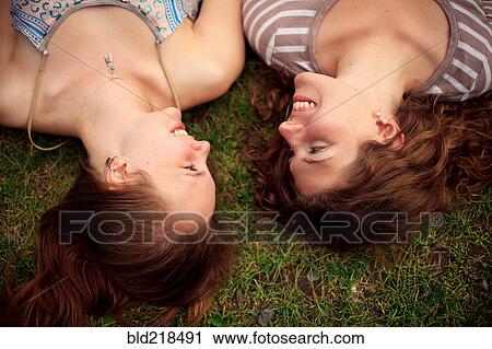 Stock Image - Close up of smiling girls laying in grass. Fotosearch