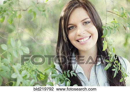 Stock Image - Close up of smiling woman standing in garden. Fotosearch