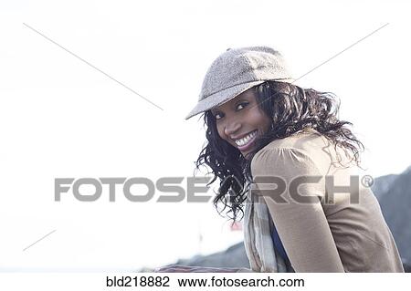 Stock Image - Close up of smiling woman wearing cap outdoors. Fotosearch