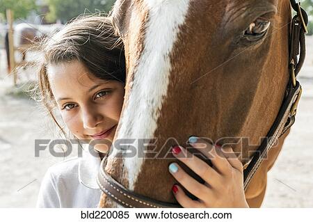 Stock Photography - Close up of teenage girl hugging horse. Fotosearch