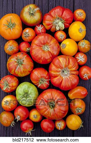 Stock Image - Close up of variety of fresh tomatoes on board. Fotosearch