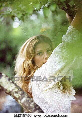 Stock Image - Close up of woman climbing tree. Fotosearch