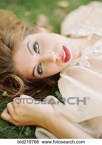 Stock Photograph - Close up of woman laying in grass. Fotosearch