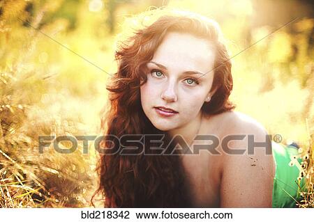 Stock Image - Close up of woman laying in tall grass. Fotosearch
