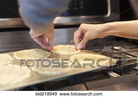 Stock Photo - Close up of woman lining pie pans on stove. Fotosearch