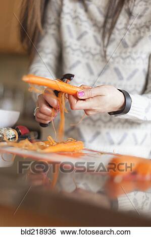 Stock Photograph - Close up of woman peeling carrot. Fotosearch