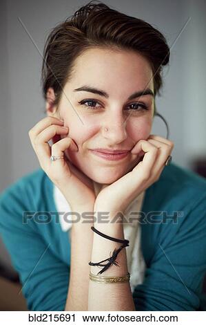 Stock Image - Close up of woman resting chin in hands. Fotosearch