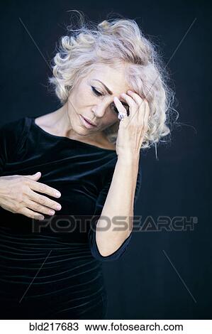 Stock Image - Close up of woman touching her forehead. Fotosearch