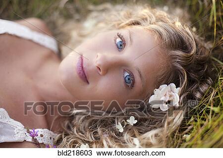 Close up of woman with blue eyes laying in grass View Large Photo Image Stock Image - Close up of woman with blue eyes laying in grass. Fotosearch
