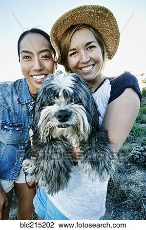 Stock Image - Close up of women smiling with dog. Fotosearch