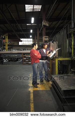 Stock Image - Co-workers talking in factory. Fotosearch