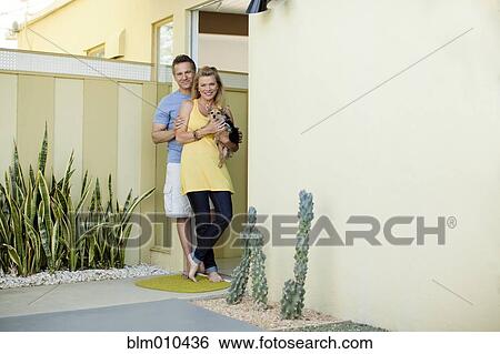 Stock Photograph - Couple and dog standing together in doorway. Fotosearch