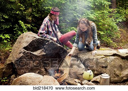 Couple building campfire in forest View Large Photo Image Stock Image - Couple building campfire in forest. Fotosearch