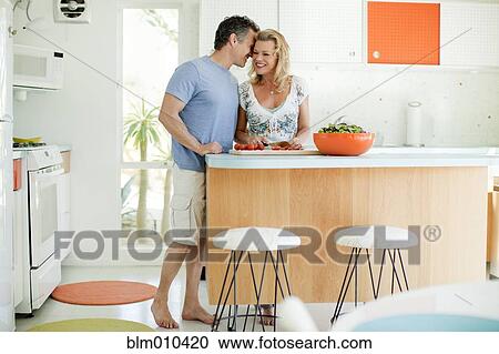 Stock Image - Couple cooking in kitchen together. Fotosearch