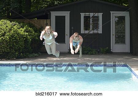 Stock Photo - Couple diving into swimming pool in backyard. Fotosearch