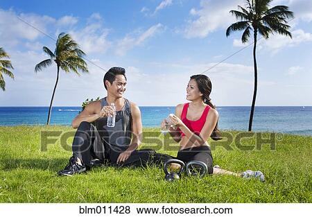 Couple drinking water after exercise at waterfront View Large Photo Image Stock Photo - Couple drinking water after exercise at waterfront. Fotosearch