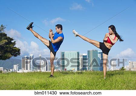 Stock Image - Couple exercising together in field. Fotosearch