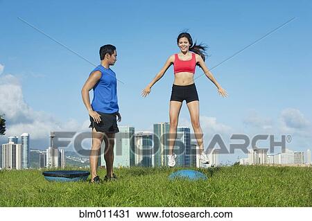 Stock Image - Couple exercising together in field. Fotosearch