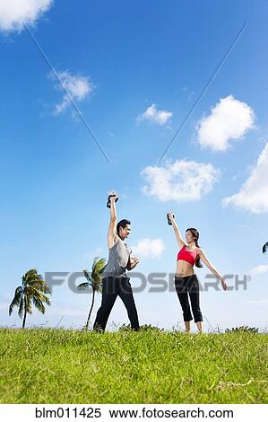 Stock Photography - Couple exercising together in field. Fotosearch