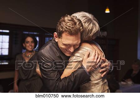 Stock Image - Couple greeting friends in restaurant. Fotosearch