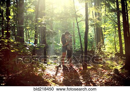 Stock Image - Couple hugging in sunny forest. Fotosearch