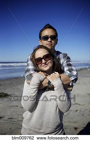 Stock Image - Couple hugging on beach. Fotosearch