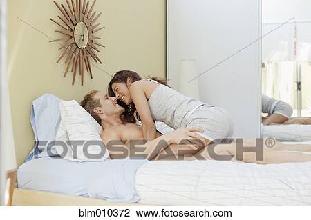 Stock Image - Couple kissing in bed. Fotosearch