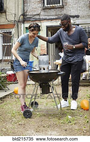 Stock Photography - Couple lighting charcoal for backyard barbecue. Fotosearch