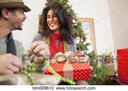 Stock Image - Couple opening Christmas gifts. Fotosearch
