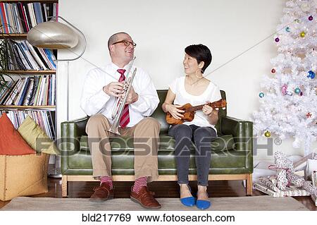 Couple playing music near Christmas tree View Large Photo Image Stock Photo - Couple playing music near Christmas tree. Fotosearch