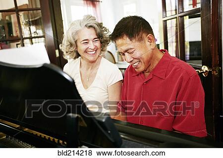Couple playing piano together in living room View Large Photo Image Stock Photo - Couple playing piano together in living room. Fotosearch