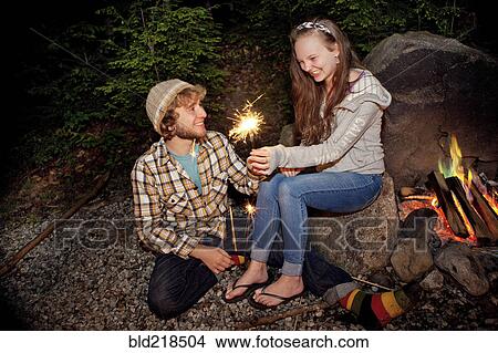Picture - Couple playing with sparkler near campfire. Fotosearch