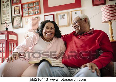 Stock Image - Couple reading book in living room. Fotosearch