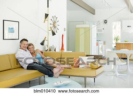 Stock Image - Couple relaxing together in living room. Fotosearch