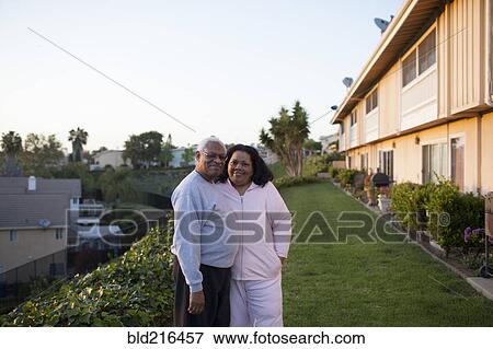 Couple smiling in backyard of apartment building View Large Photo Image Stock Photo - Couple smiling in backyard of apartment building. Fotosearch