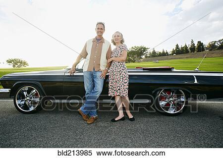 Couple smiling near classic convertible View Large Photo Image Stock Photography - Couple smiling near classic convertible. Fotosearch