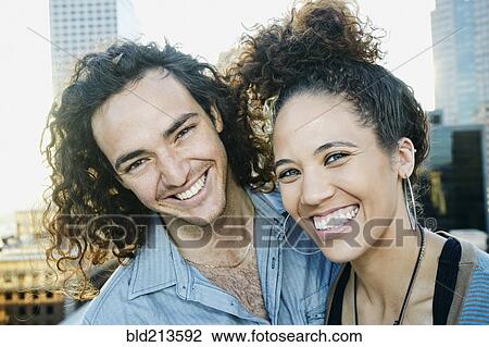 Stock Image - Couple smiling on urban rooftop. Fotosearch