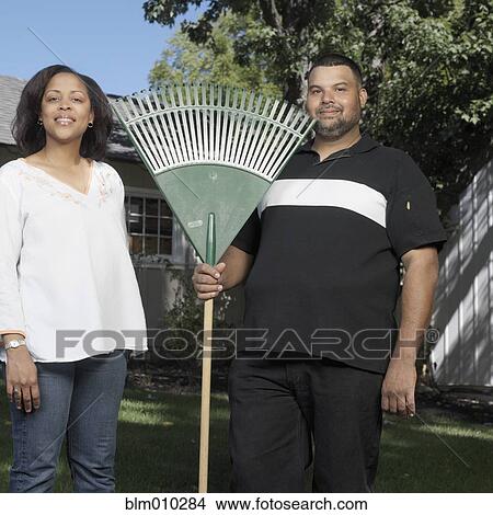 Couple standing in yard with rake View Large Photo Image Picture - Couple standing in yard with rake. Fotosearch