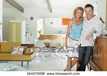 Couple standing together in living room View Large Photo Image Stock Photo - Couple standing together in living room. Fotosearch