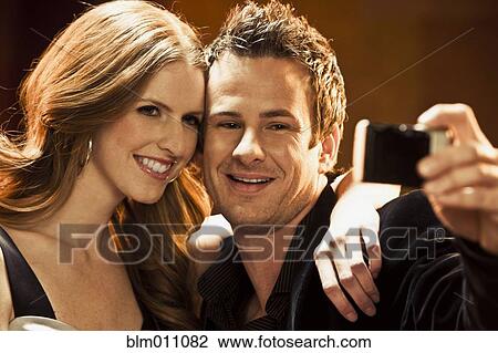 Couple taking self-portrait with camera in nightclub View Large Photo Image Stock Image - Couple taking self-portrait with camera in nightclub. Fotosearch