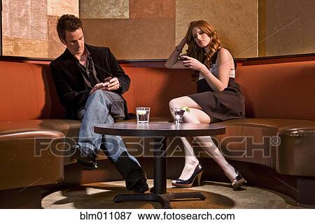 Couple text messaging in nightclub View Large Photo Image Stock Photo - Couple text messaging in nightclub. Fotosearch
