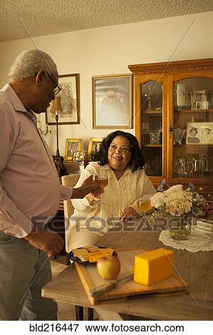 Stock Photo - Couple toasting each other with wine in kitchen. Fotosearch