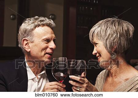 Stock Image - Couple toasting with red wine in restaurant. Fotosearch