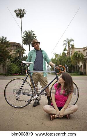 Stock Photo - Couple together outdoors with bicycle. Fotosearch