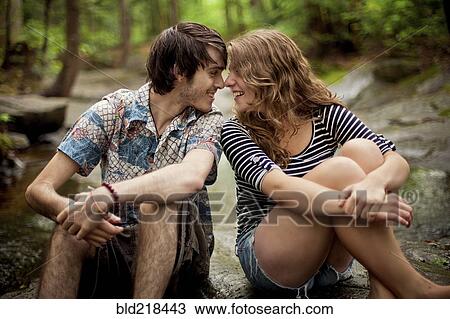 Stock Image - Couple touching foreheads on boulders in forest. Fotosearch