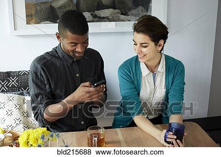Couple using cell phone at table View Large Photo Image Stock Photo - Couple using cell phone at table. Fotosearch
