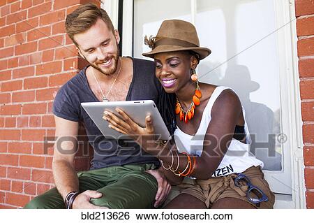 Stock Photograph - Couple using digital tablet outdoors. Fotosearch