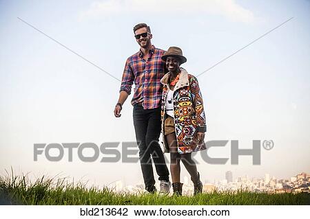 Stock Image - Couple walking together in grassy field. Fotosearch