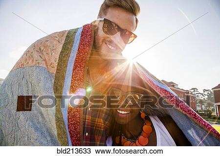 Couple wrapped in blanket smiling outdoors View Large Photo Image Stock Image - Couple wrapped in blanket smiling outdoors. Fotosearch